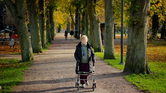 Äldre kvinna med rullator på promenad