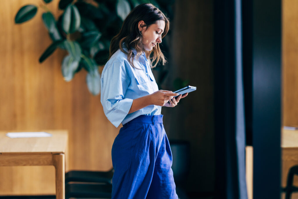 Woman Standing Indoors Using a Tablet Device in a Contemporary Office Space