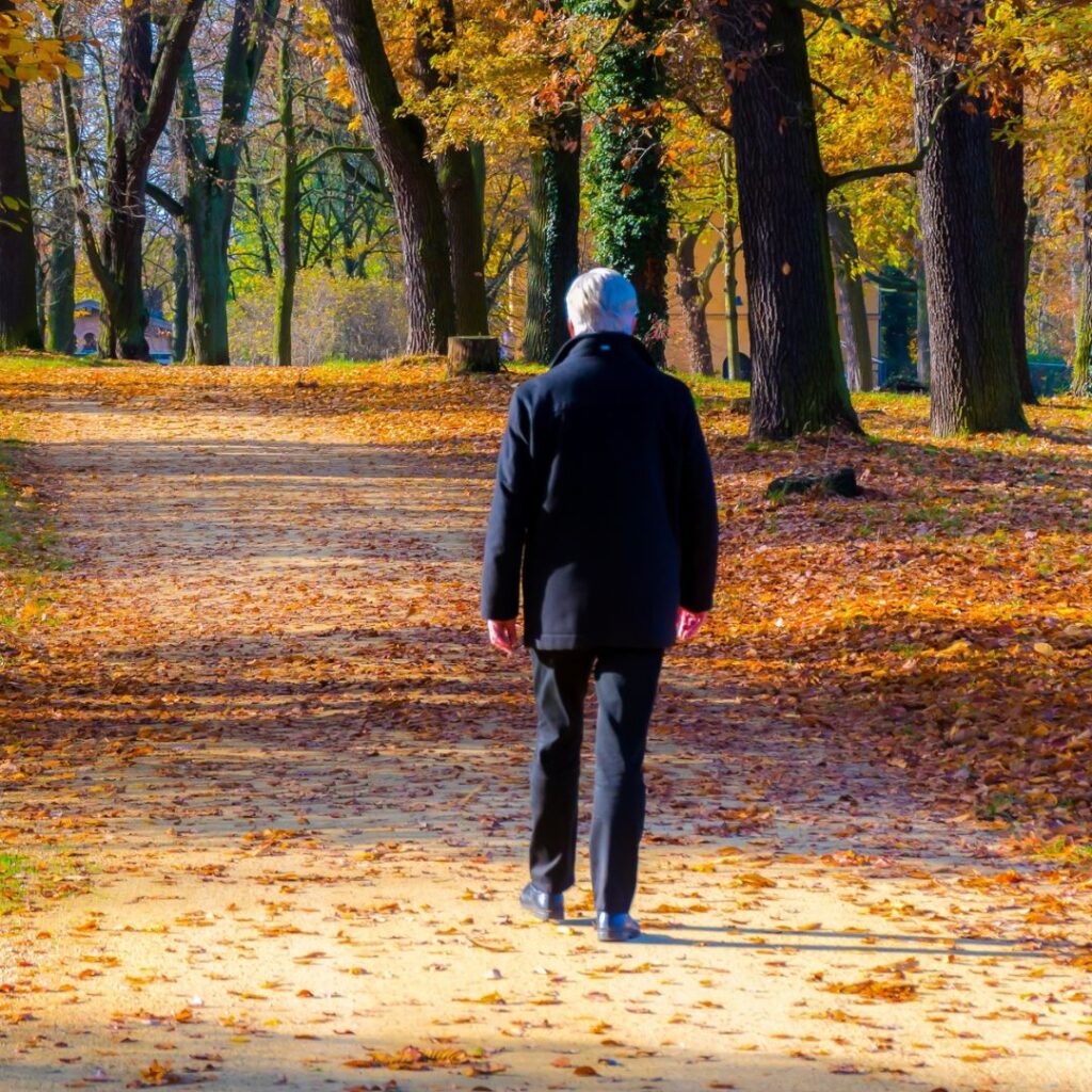 Homme âgé atteint de démence marchant seul sur une route en automne