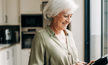Femme âgée souriant tout en utilisant une tablette de soins équipée d'une technologie.