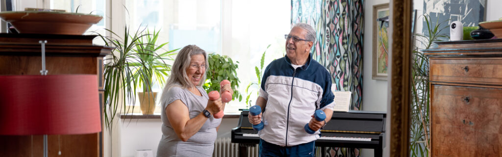 Ein Mann und eine Frau heben Gewichte, die Frau trägt einen Careium-Enzo-Anhänger