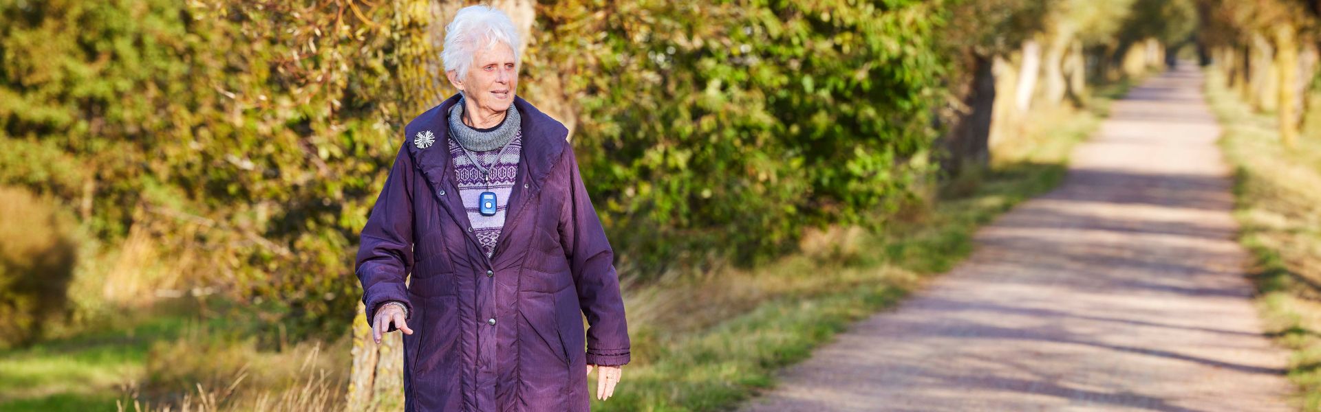 elderly woman walking in the sun on a gravel road