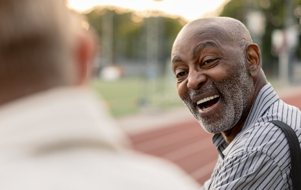 an elderly man in an outdoor environment smiling at someone