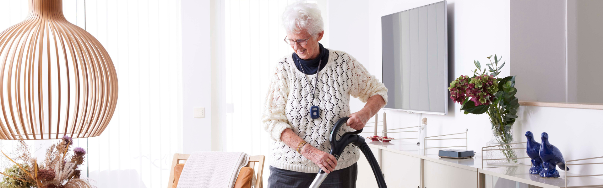 oudere vrouw die Abby-hanger draagt, stofzuigt
