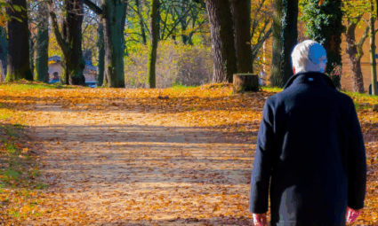Oudere man met diagnose dementie loopt alleen op weg in herfst