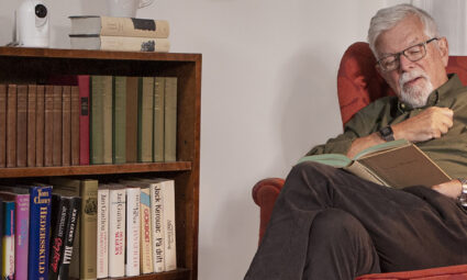 Hombre mayor leyendo con una Careium Visit en segundo plano