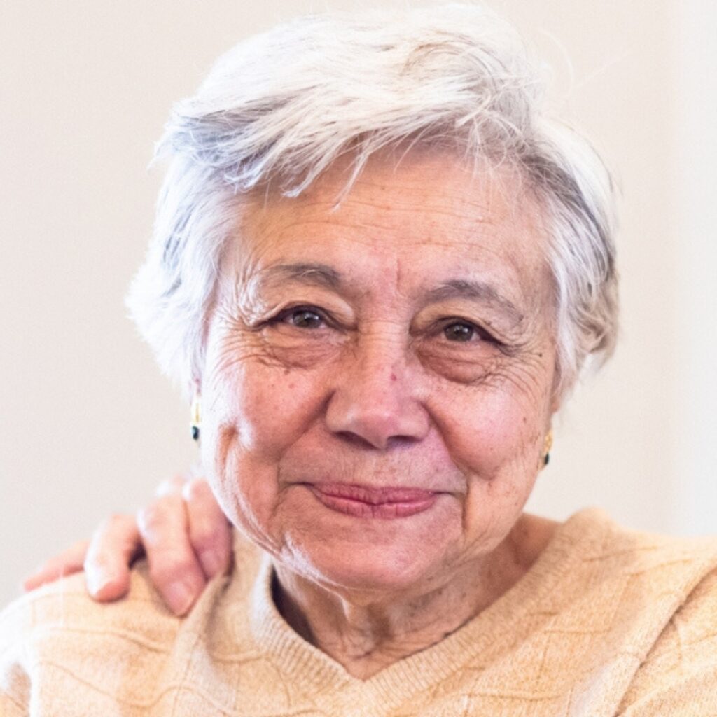 older woman looking at camera wearing a yellow sweater