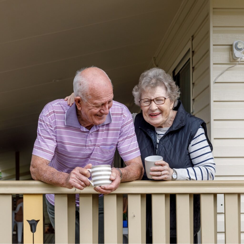 una pareja de ancianos en un porche tomando café y riendo