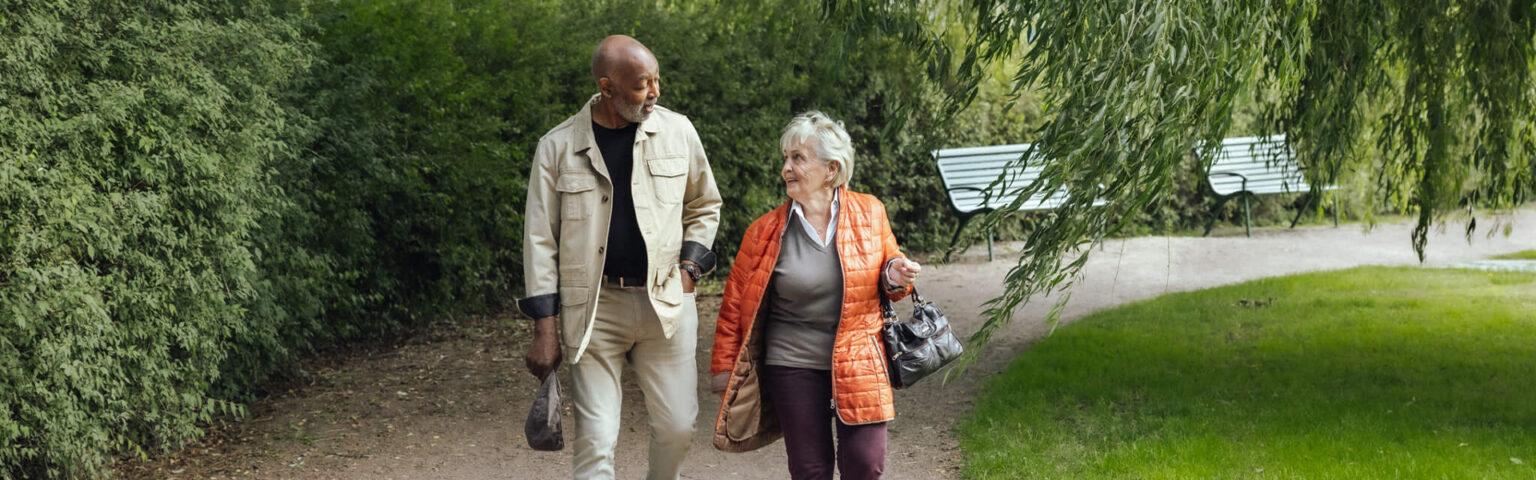 A man and woman walking on a path in a park, happily talking to each other