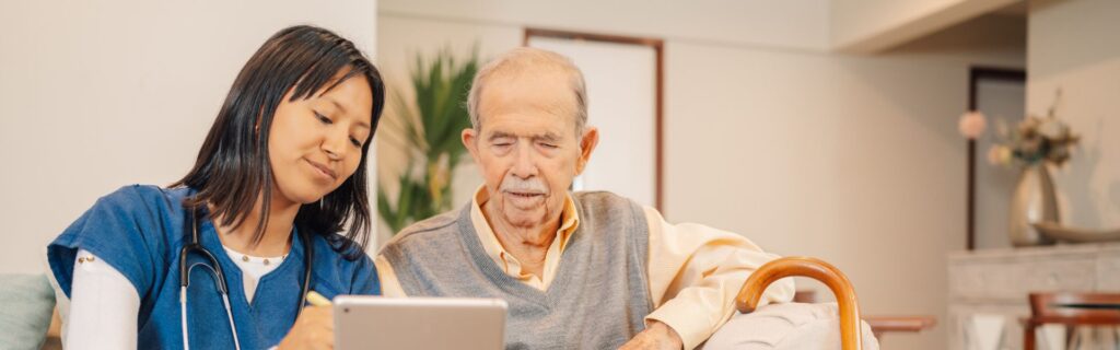 Female care giver showing older man a telecare device