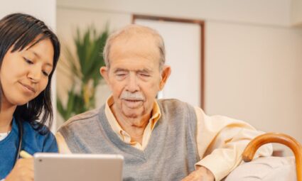 Female care giver showing older man a telecare device
