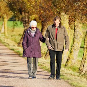 a man and woman walking on a road lined with trees