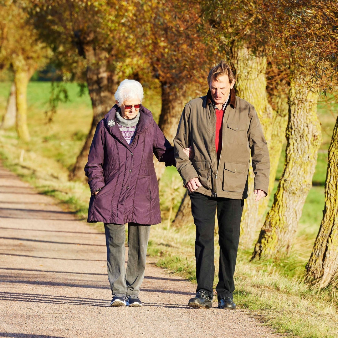 a man and woman walking on a road lined with trees