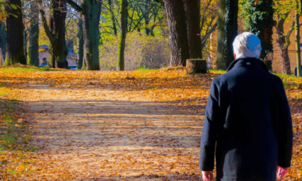Elderly man with dementia diagnosis walking alone on road in autumn