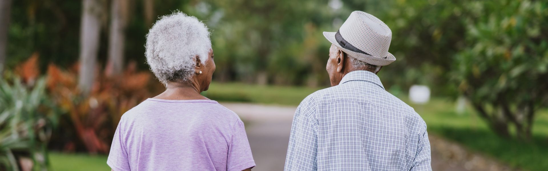 an older man with a gray hat and an elderly woman in a pink shirt on a walk