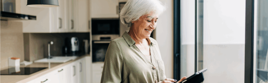 Older woman smiling while using a technology enabled care tablet