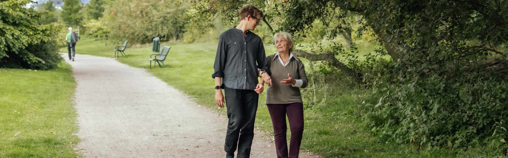 older woman and younger man walking in park