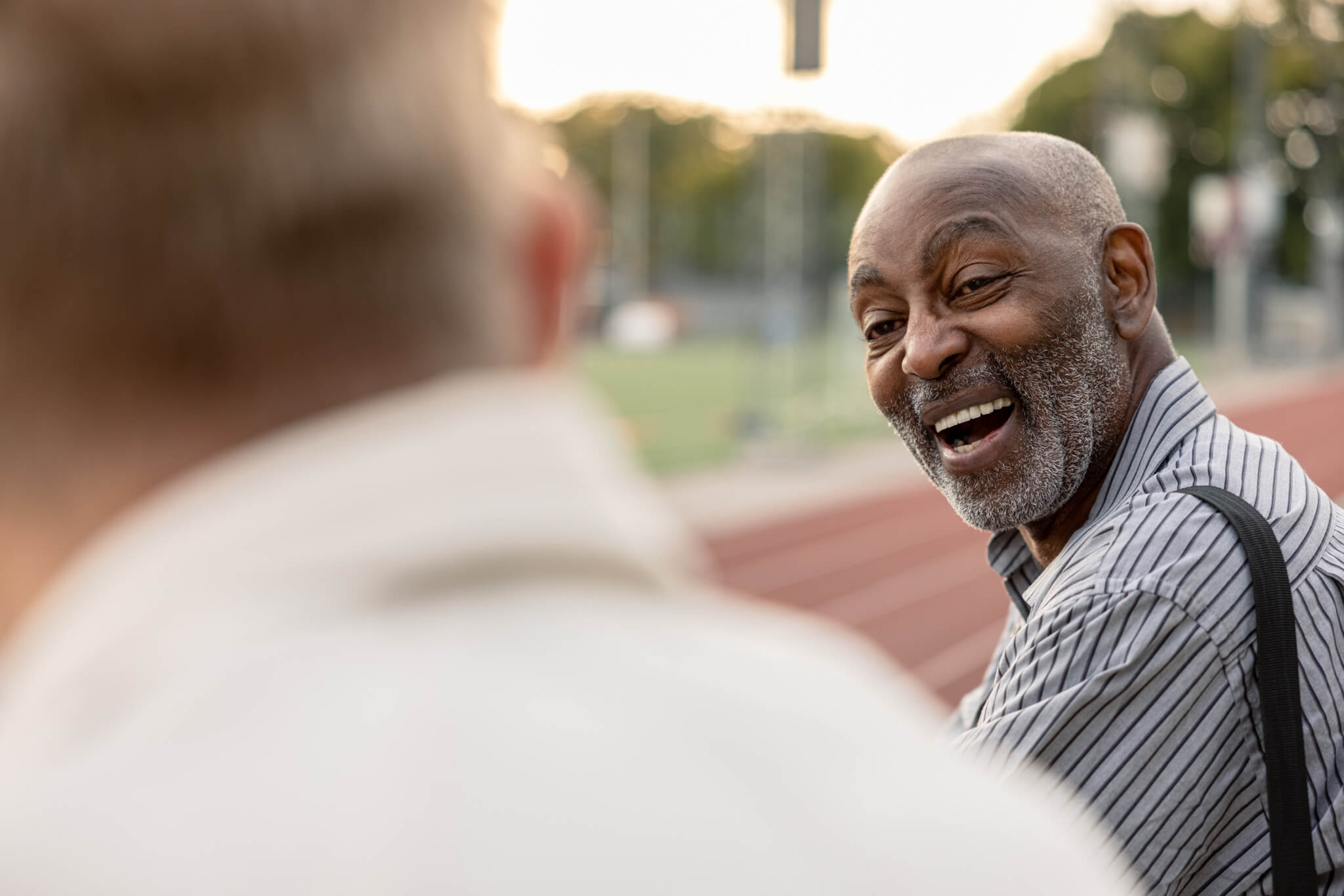 Eldre person ler ved en fotballbane