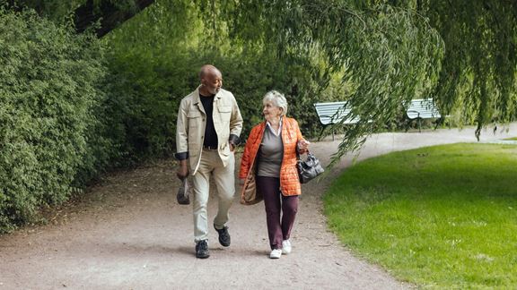 Äldre par promenerar i en park
