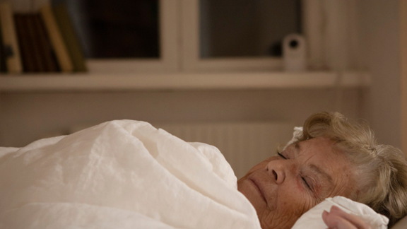 Older woman sleeping with Visit in background