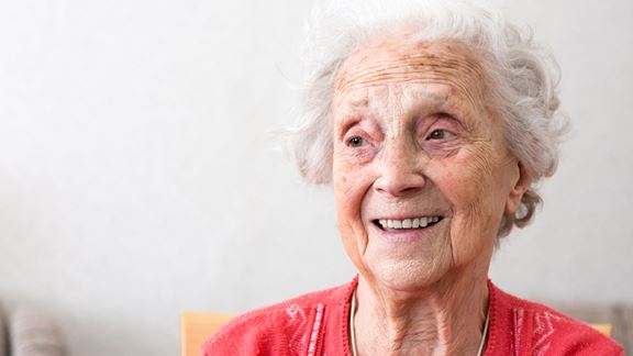 Senior kvinna med röd tröja som ler