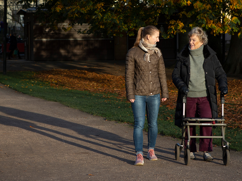 Äldre kvinna och ung kvinna pratar och promenerar utomhus