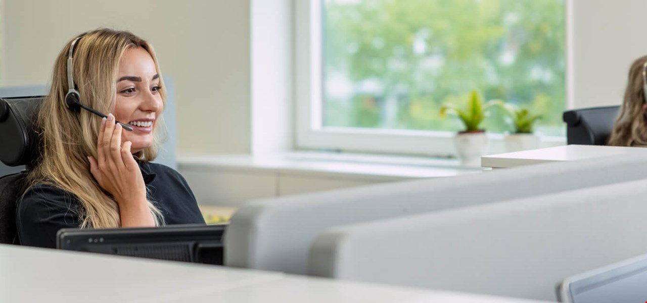 Young smiling woman with headset in alarm receiving centre