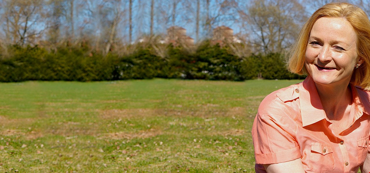 Femme d'une cinquantaine d'années souriant dans un jardin ensoleillé